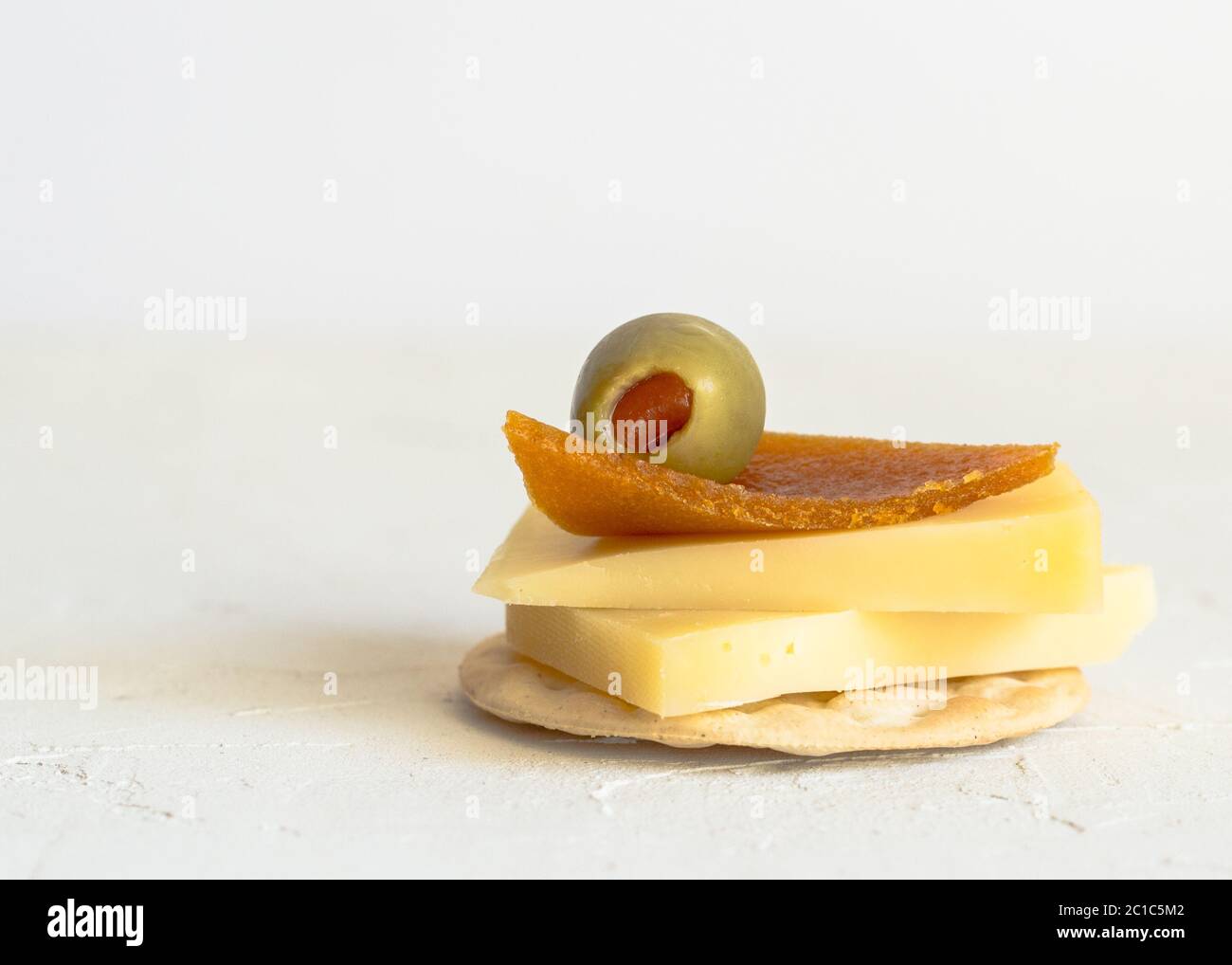 Käse auf Cracker mit piment Gefüllte grüne Oliven und getrocknete Pfirsich roll Dekoration isoliert auf weiss Stockfoto