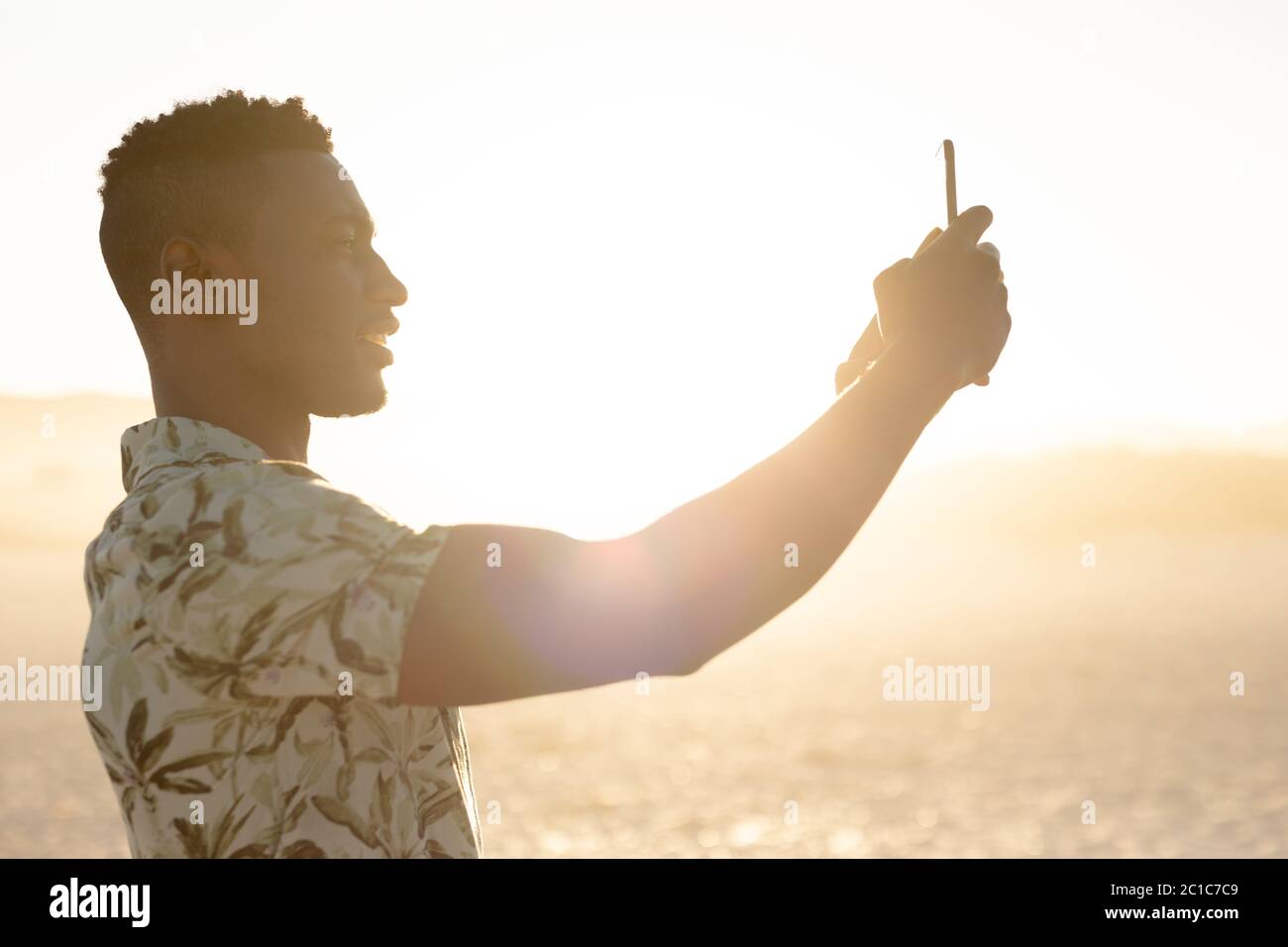 Afrikanischer amerikanischer Mann, der am Strand fotografiert Stockfoto