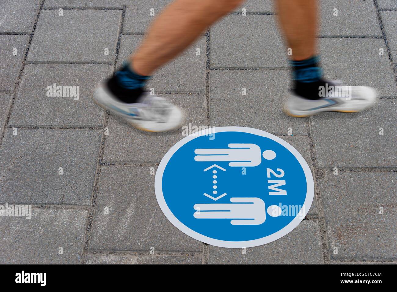 Schild, das am Boden aufgedruckt ist und die Menschen informiert, während der Covid-19-Pandemie einen Abstand von 2 Metern voneinander zu halten. Stockfoto