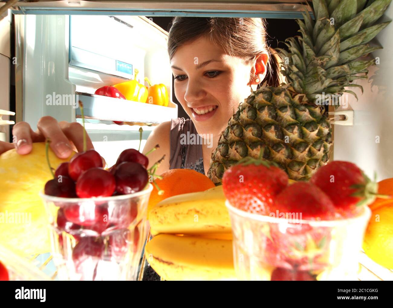 Mädchen bekommt Obst aus dem Kühlschrank Stockfoto