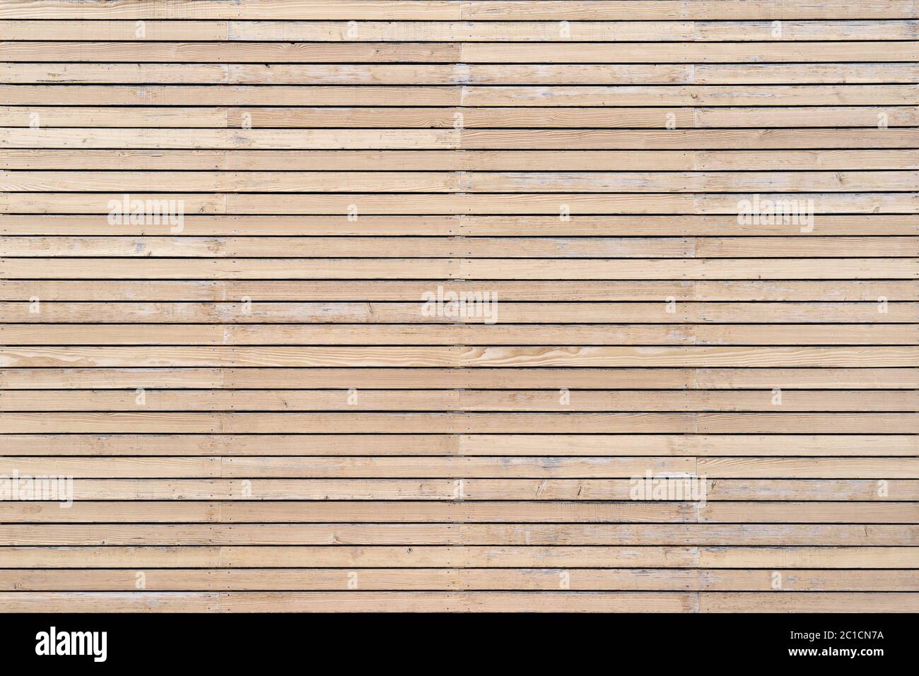 Helle, leicht verwitterte Holzfassade mit horizontalem Gitter