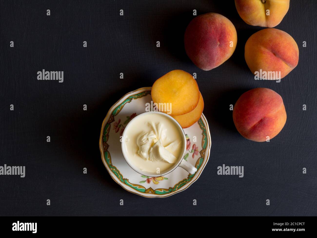 Ganze und aufgeschnittene Pfirsiche und Creme auf Schwarz tisch Foto anzeigen Stockfoto