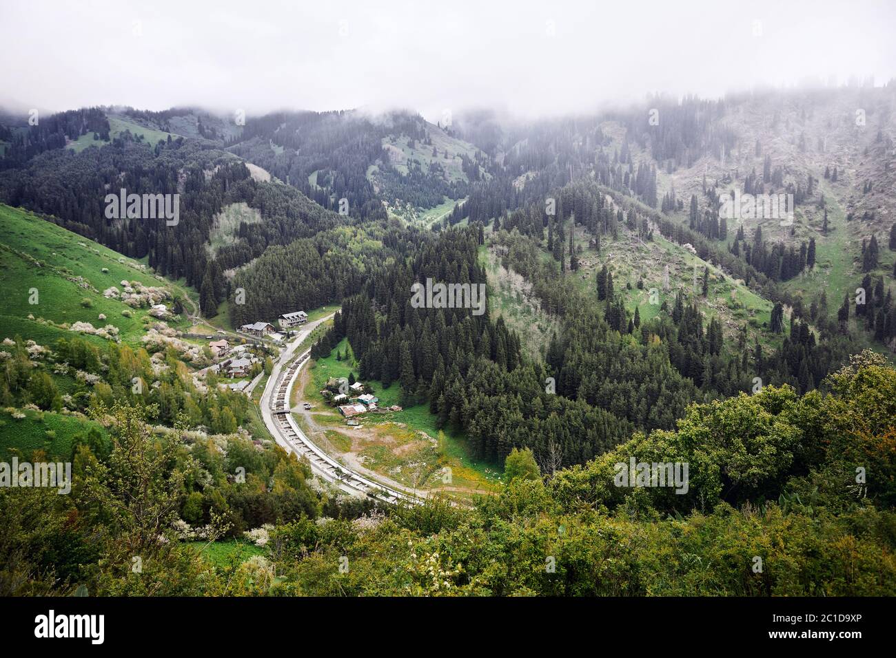 Luftaufnahme des alpinen Dorfes und des Flusses in den Bergen bei nebligen Wolken. Foto mit Drone aufgenommen Stockfoto