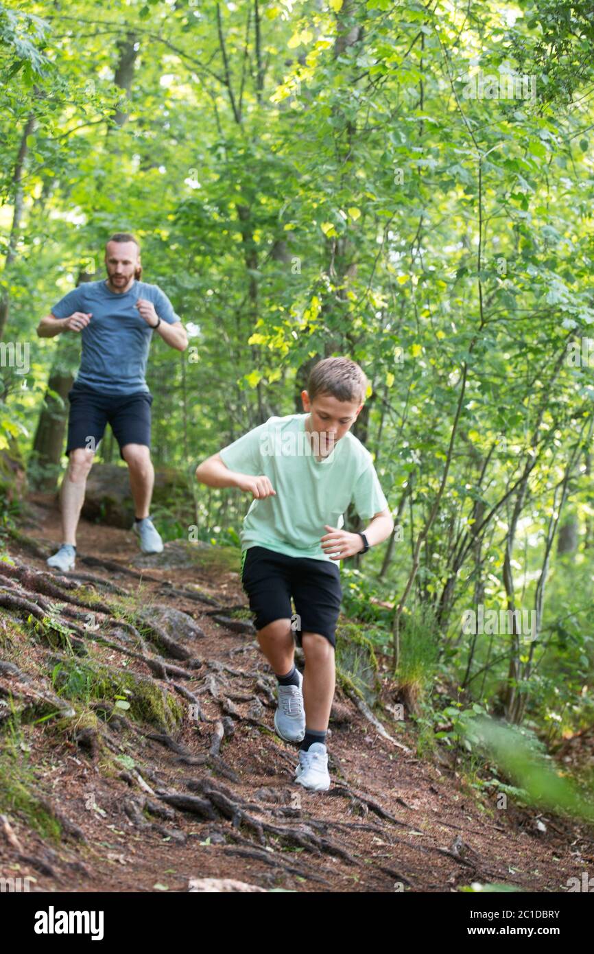 Vater und Sohn laufen gemeinsam im Wald, Pflege, Sport, Elternschaft, gesundes Lebenskonzept Stockfoto