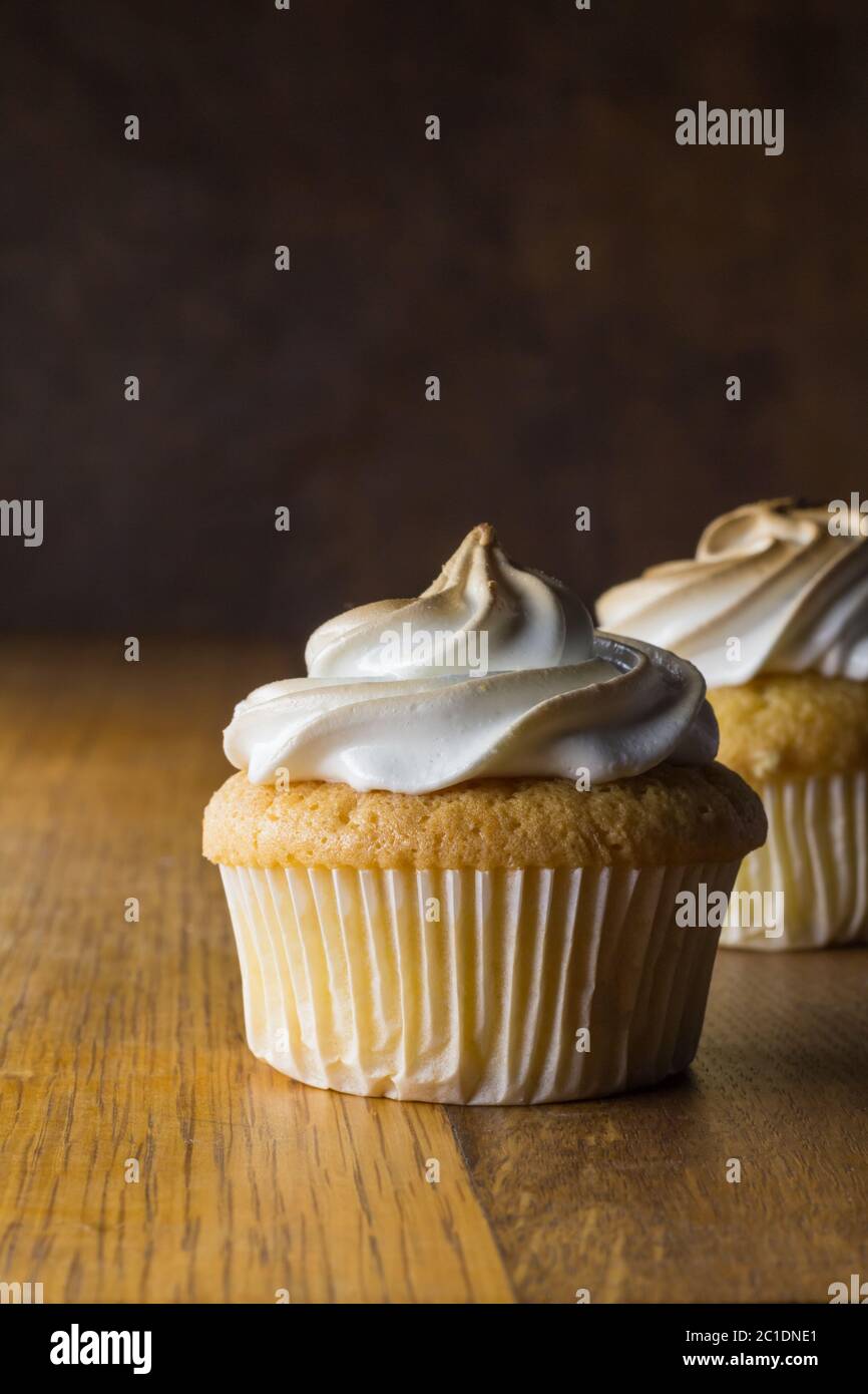 Tasse Kuchen mit weißen Baiser Zuckerguss auf Holztisch, konzentrieren sich auf Front Cupcake Stockfoto