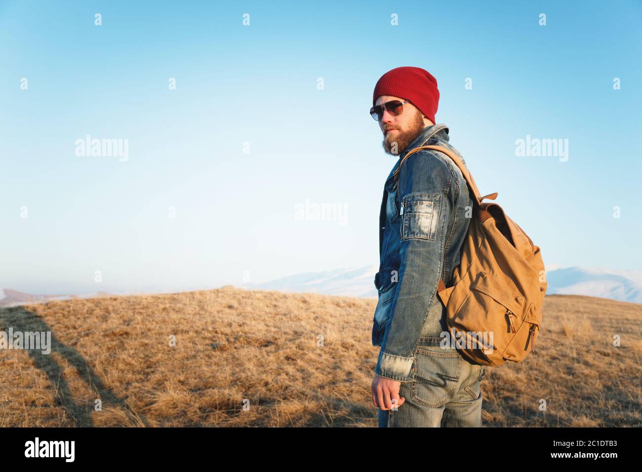 Modehortrait eines bärtigen Hipster-jungen Mannes mit Sonnenbrille, Rucksack und Hut auf einem Hintergrund mit Copyspase im mou Stockfoto