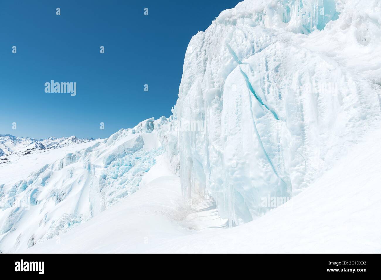 Ein großer schneebedeckter Gletscher hoch in den Bergen vor dem Hintergrund des Kaukasus-Gebirges und des blauen Himmels Stockfoto