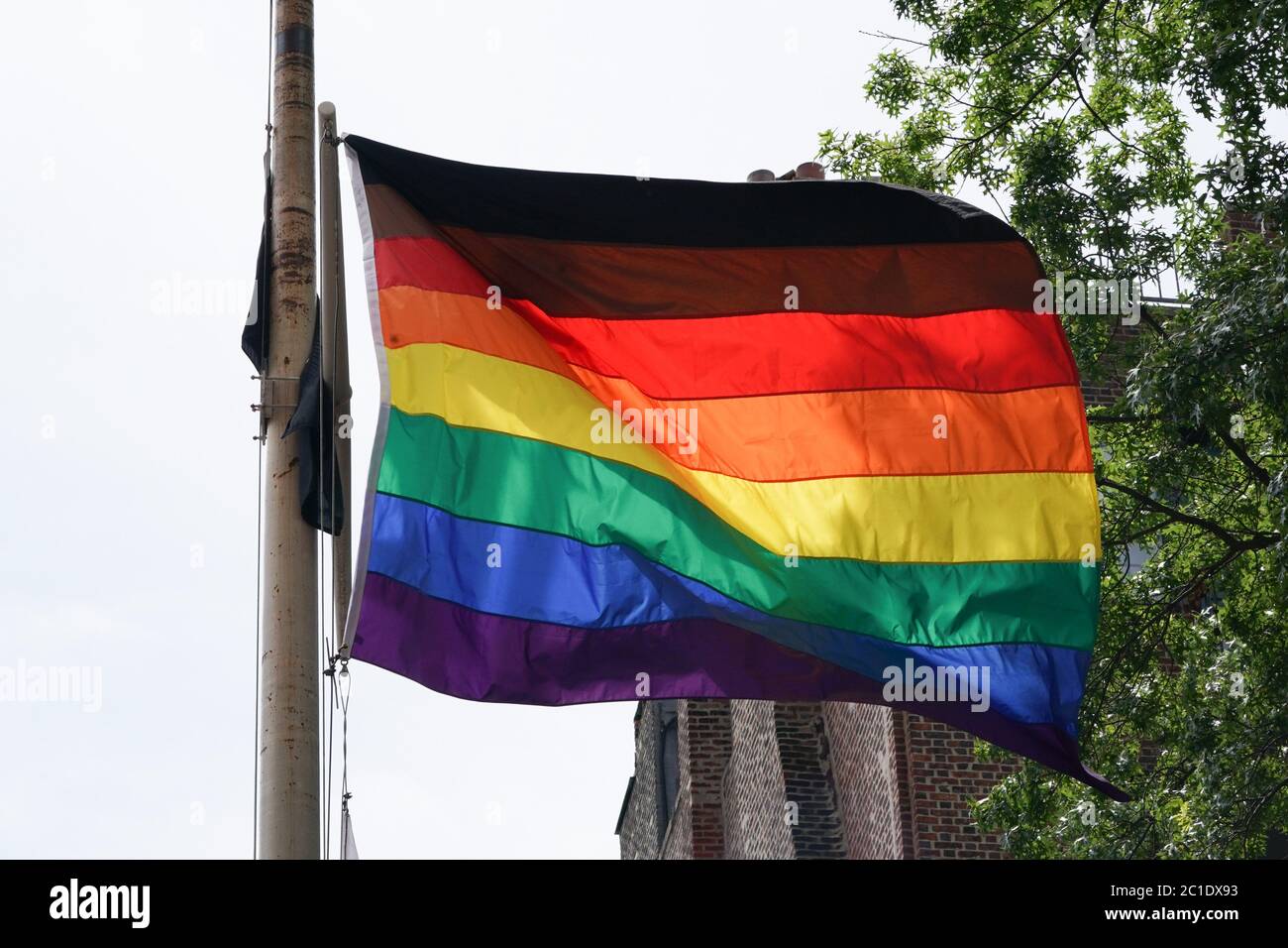 New York, NY, USA. Juni 2020. Die Regenbogenfahne mit schwarzem und braunem Streifen, die die Themen der Menschen in der LBGTQ-Gemeinschaft unterstreicht, fliegt am Stonewall National Monument. Das Stonewall Inn, die Schwulenbar & National Historic Landmark, Schauplatz der Unruhen von 1969, die die Bewegung für Homosexuelle in New York ins Leben gerufen haben, da der Oberste Gerichtshof der Vereinigten Staaten am 15. Juni 2020 entscheidet, dass Arbeitgeber LBGTQ-Arbeitnehmer nicht diskriminieren können. Quelle: Bryan Smith/ZUMA Wire/Alamy Live News Stockfoto