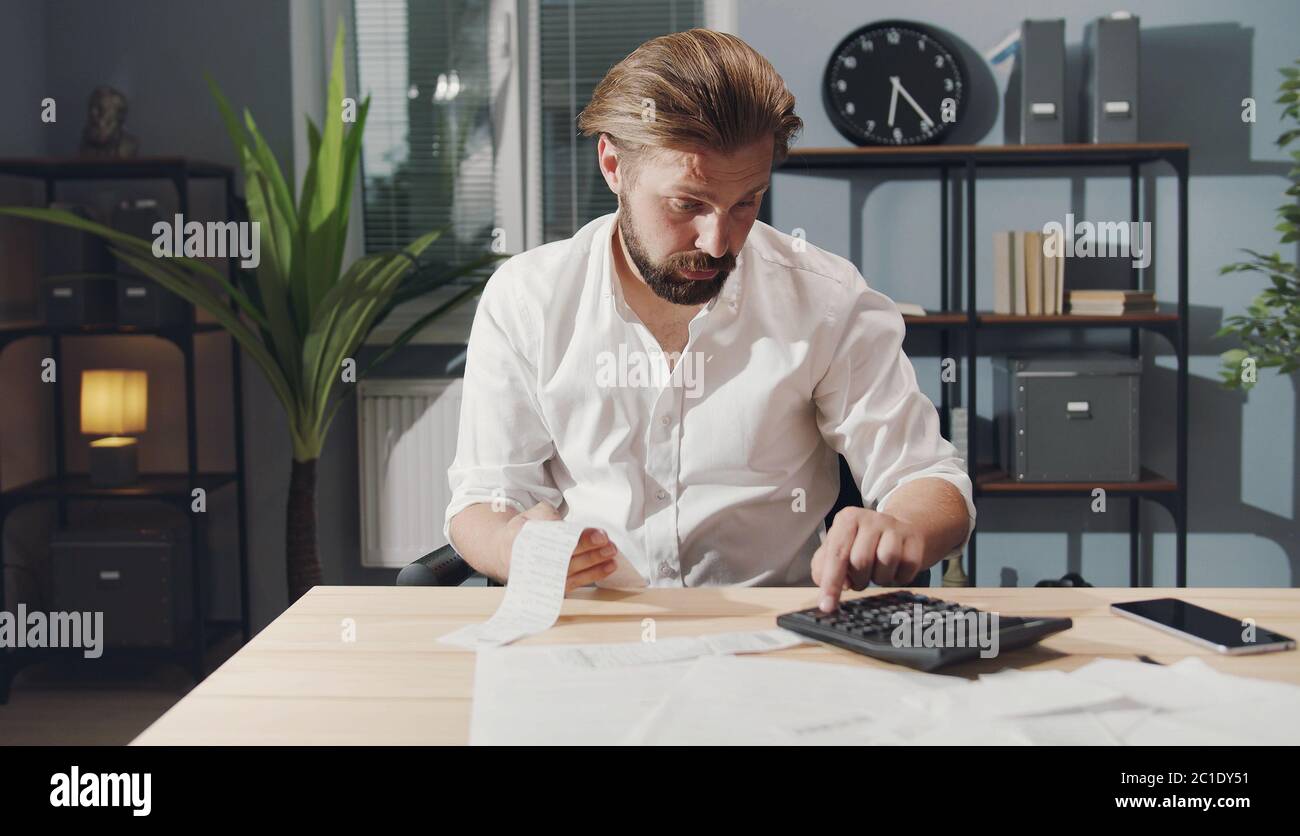 Geschäftsmann, der Zahlen auf dem Rechner überprüft Stockfoto