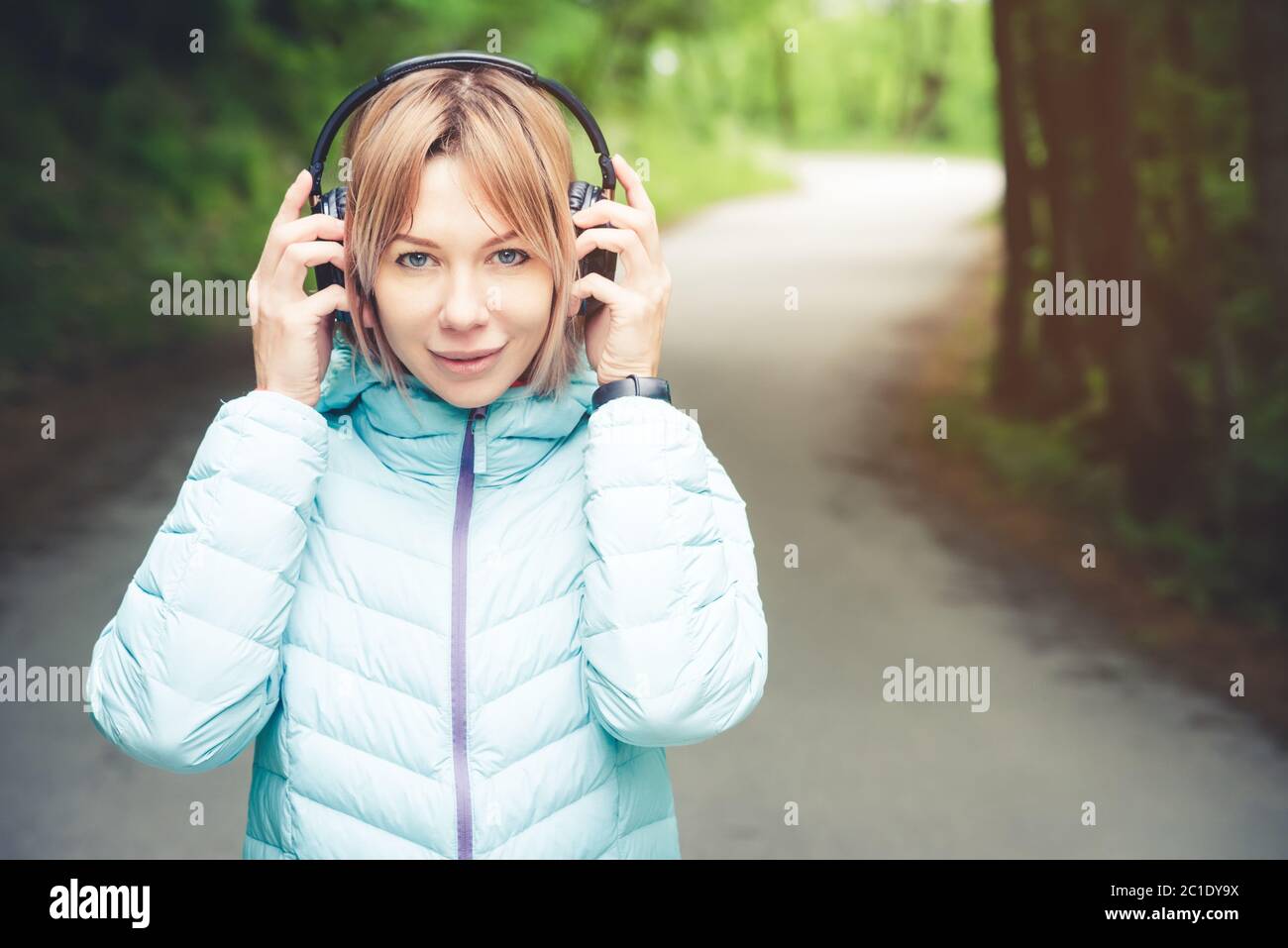 Portrait eines attraktiven Sportmädchen blond in einer leichten Jacke unten Dressing bluetooth Kopfhörer mit Musik oder der Soun Stockfoto