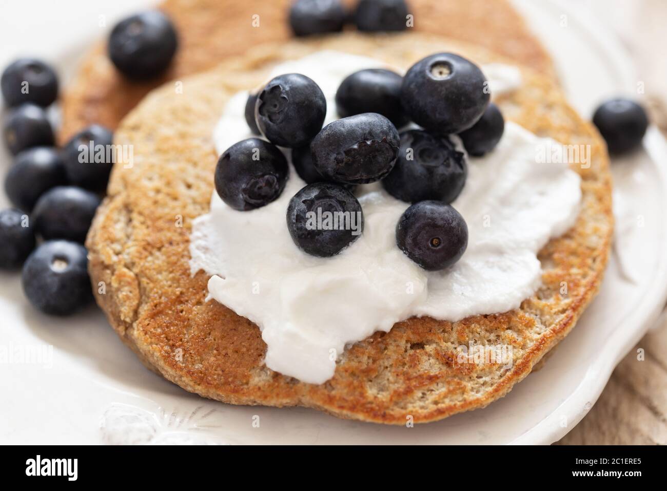 Nahaufnahme der Haferflocken Pfannkuchen mit Joghurt und Heidelbeeren. Geringe Schärfentiefe. Horizontale Zusammensetzung. Stockfoto