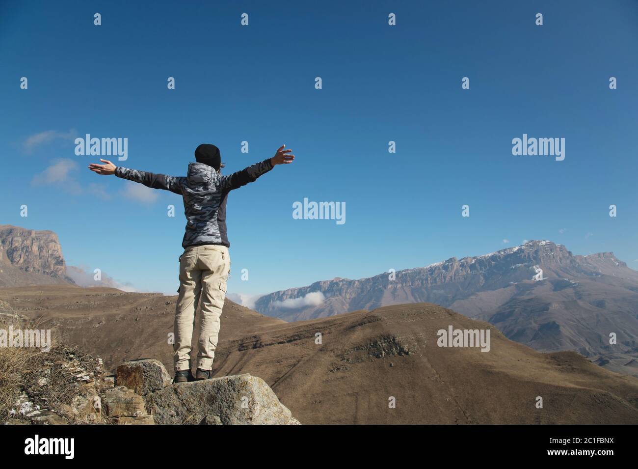 Ein Applaus einer jungen Backpacker-Frau auf einem weitläufigen Berggipfel. Freiheit und Sieg vor dem Hintergrund o Stockfoto