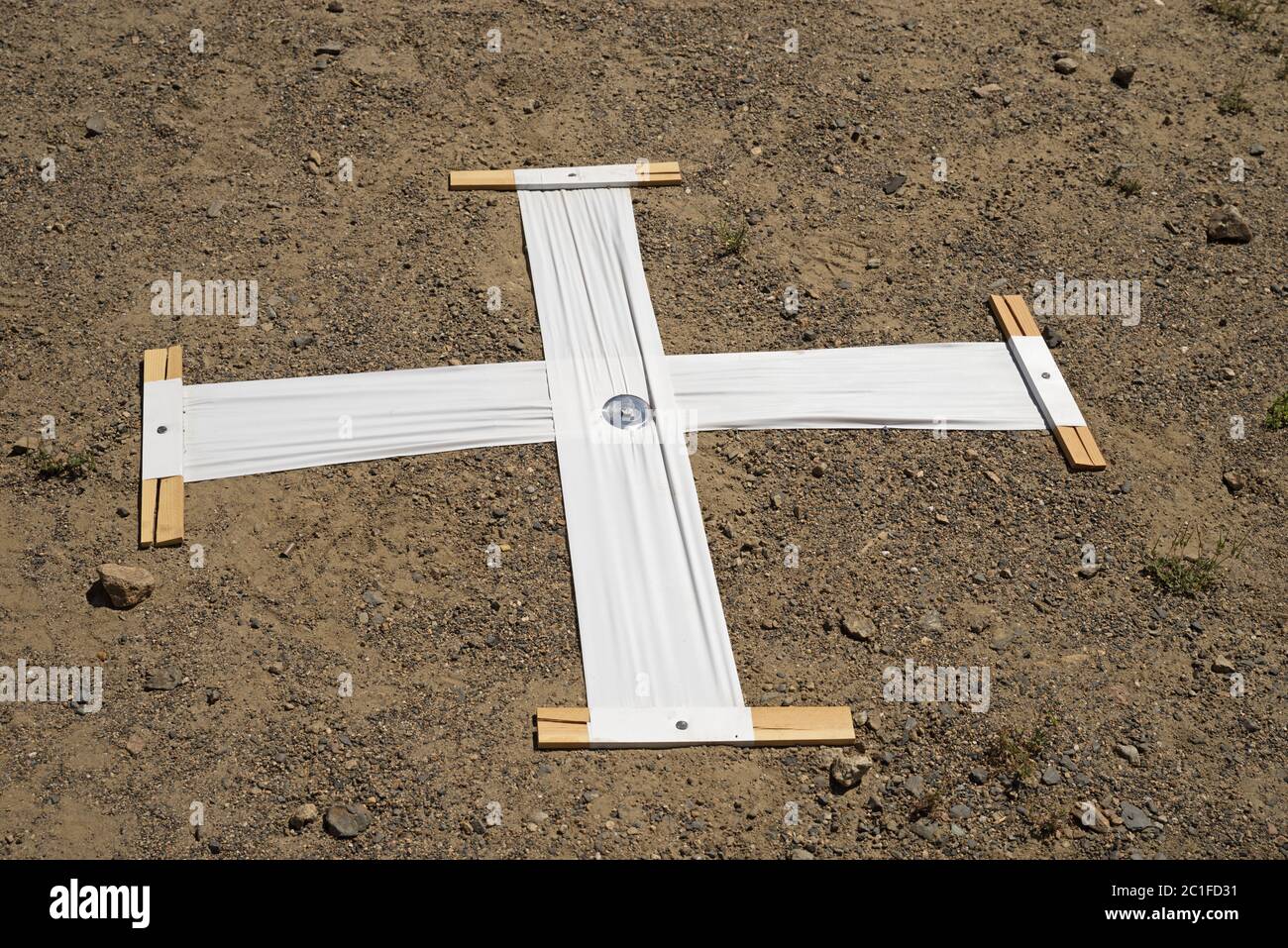 Luftbildmarkierung, bestehend aus einem weißen Kunststoffkreuz, das auf den Boden genagelt wurde, um in Luftaufnahmen zu erscheinen Stockfoto