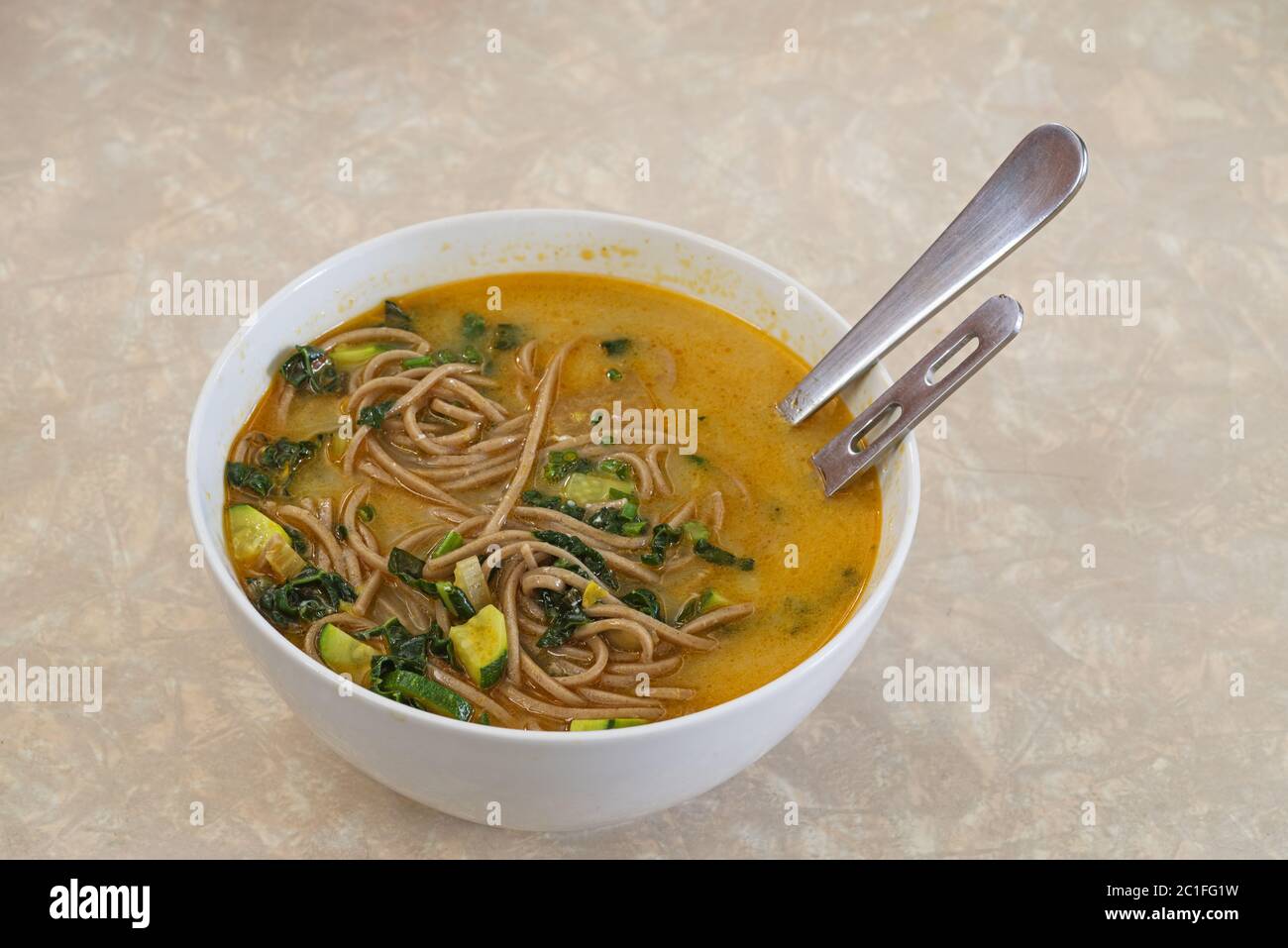 Schüssel mit hausgemachter Suppe mit reichhaltigem Brühgemüse und Soba-Nudeln Stockfoto