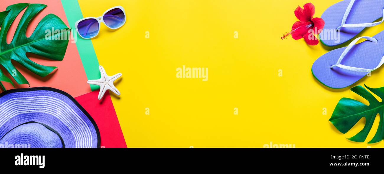 Flip-Flops und Hut und tropische Blätter - Strandzubehör im Minimal Colorful Design Stockfoto