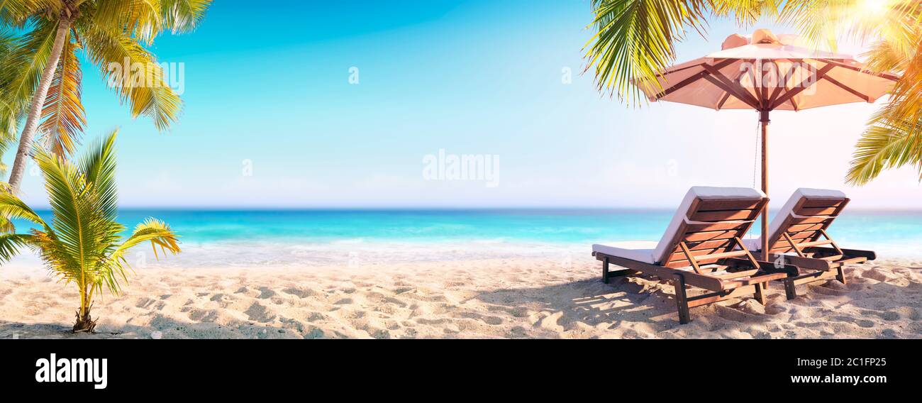 Liegestühle Und Sonnenschirm Mit Palmen Im Tropical Beach Stockfoto