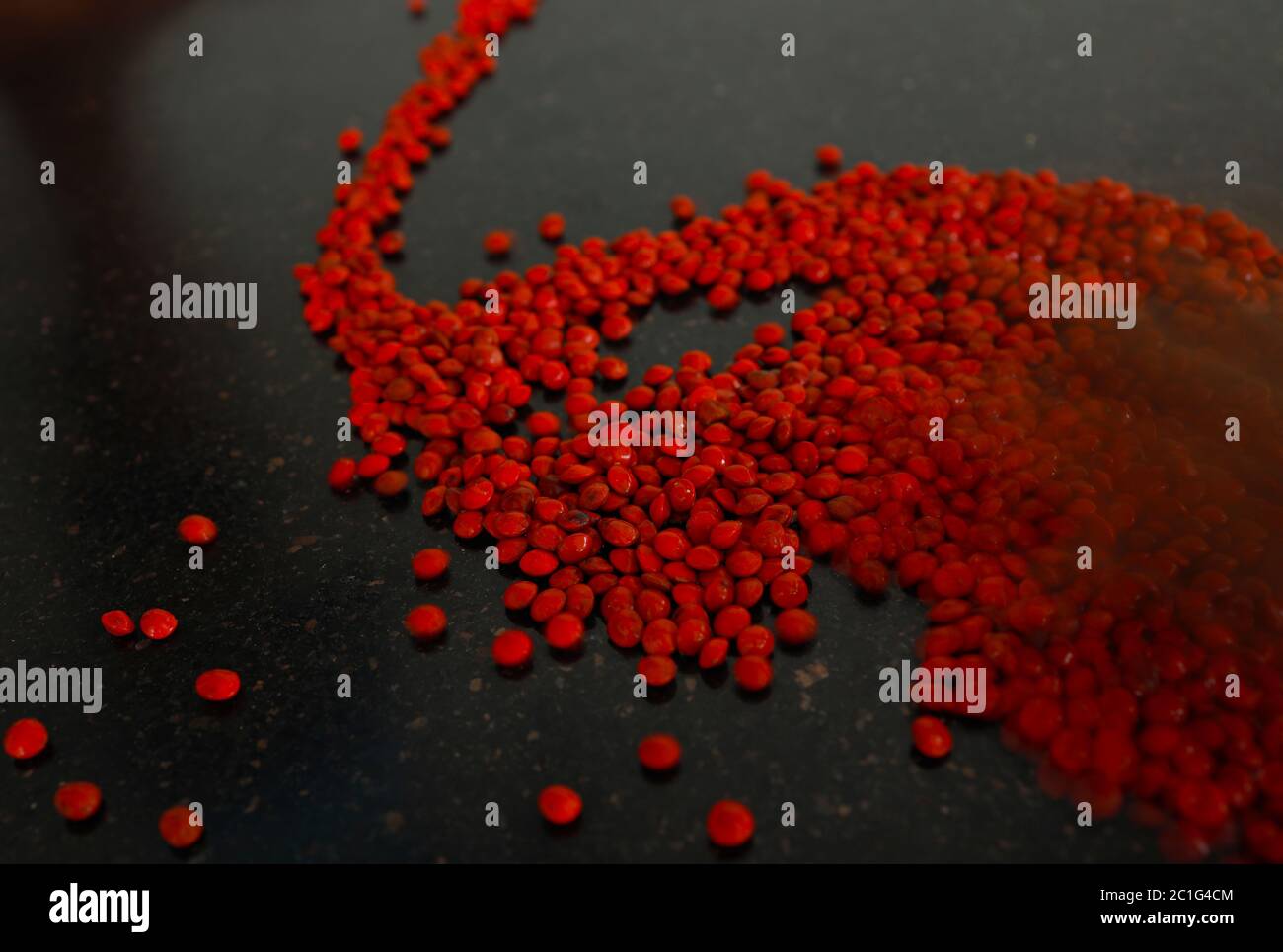 Rote Sandelholz (Adenanthera pavonina) Samen isoliert auf schwarzem Hintergrund. Manchadi, Manjadi, Manjetti, Pfauenblumenzaun, Acacia Coral, Anikundum Stockfoto