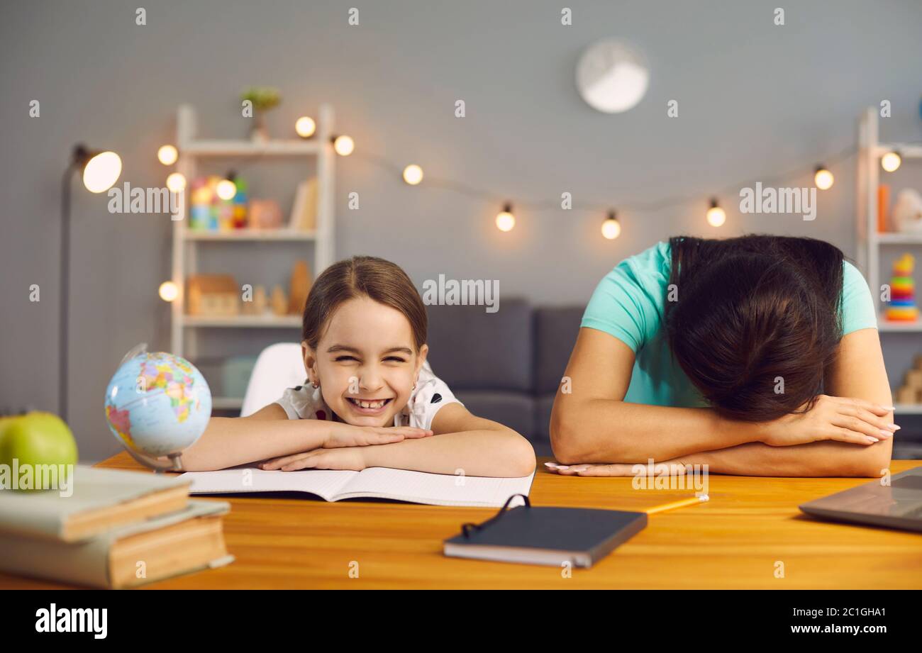 Stress Arbeit mit Kindern im Home Office. Müde Mutter schläft auf einem Desktop freche Tochter lächelnd Blick auf die Kamera im Home Office. Stockfoto