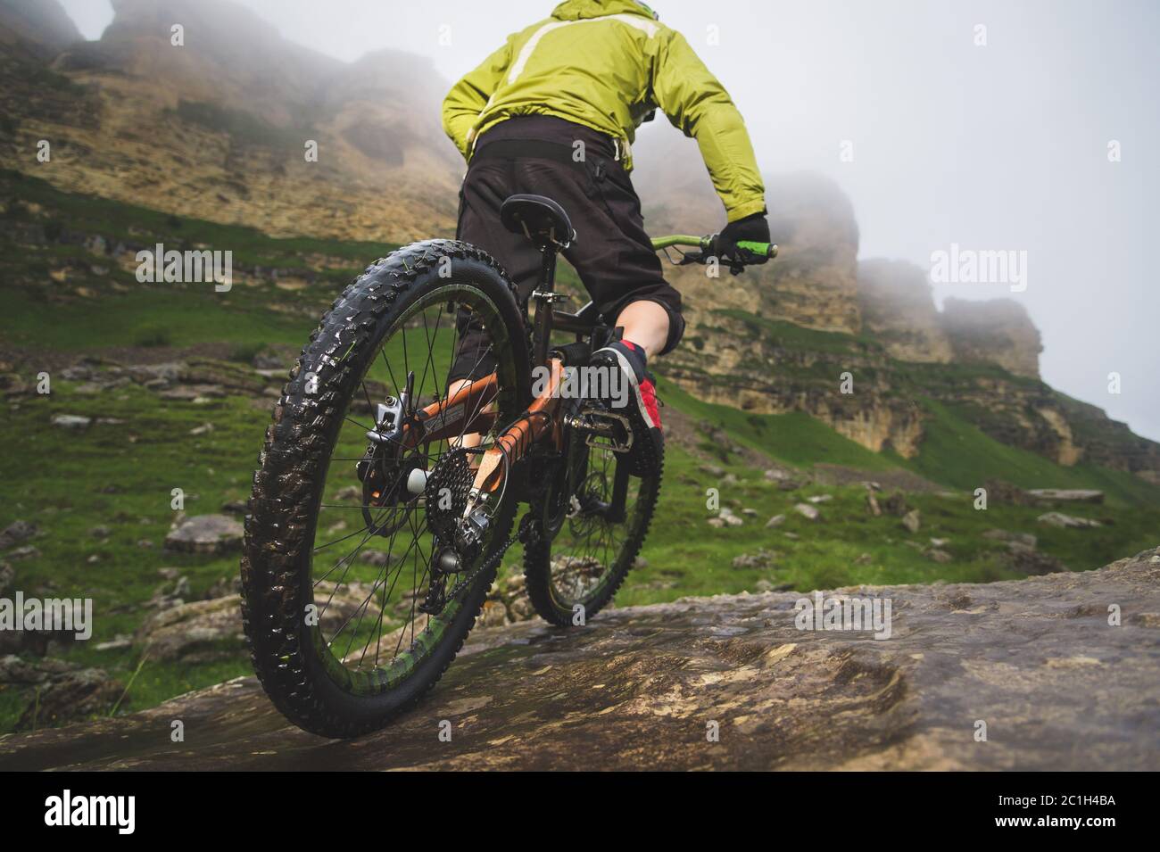 Beine von Radfahrer und Hinterrad Nahaufnahme des hinteren mtb-Bikes in den Bergen vor dem Hintergrund von Felsen bei nebligen Wetter. Die c Stockfoto