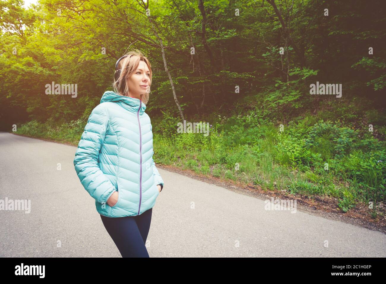 Portrait eines attraktiven Sportmädchen blond in einer leichten Jacke unten Dressing bluetooth Kopfhörer mit Musik oder der Soun Stockfoto