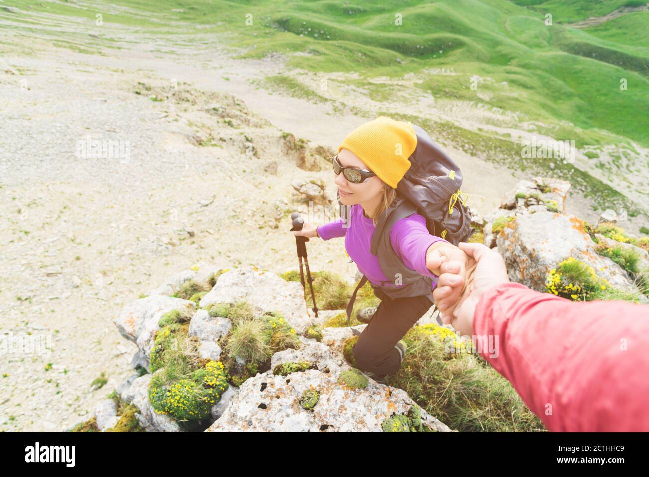 Ein Bergsteiger hilft einer jungen Bergsteigerin, den Gipfel des Berges zu erreichen. Ein Mann gibt einer Frau eine helfende Hand. Blick von oben Stockfoto