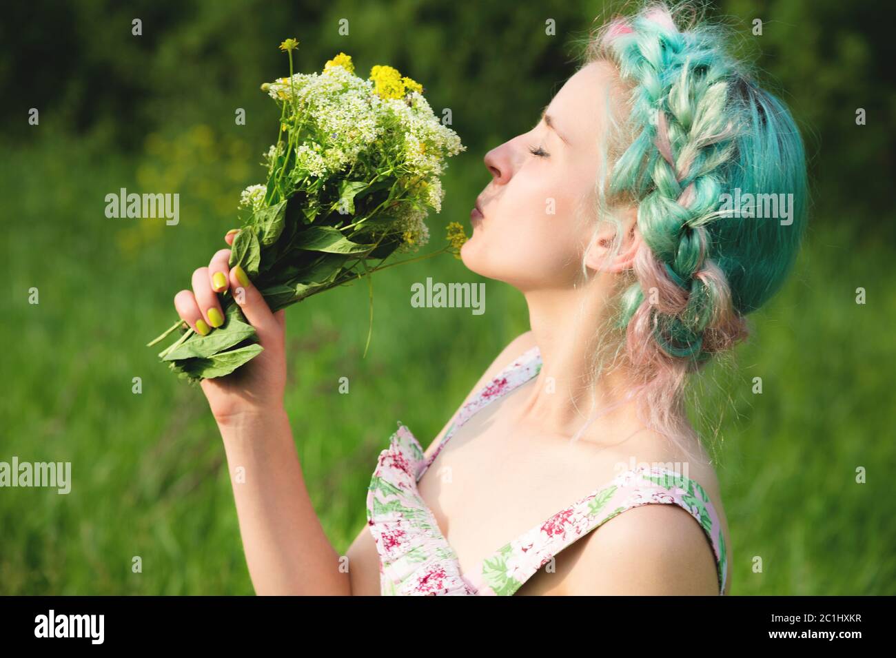Nettes junges Mädchen schnüffelt einen Strauß von Feldgräsern in der Natur. Harmonie und Genuss in der Natur Stockfoto