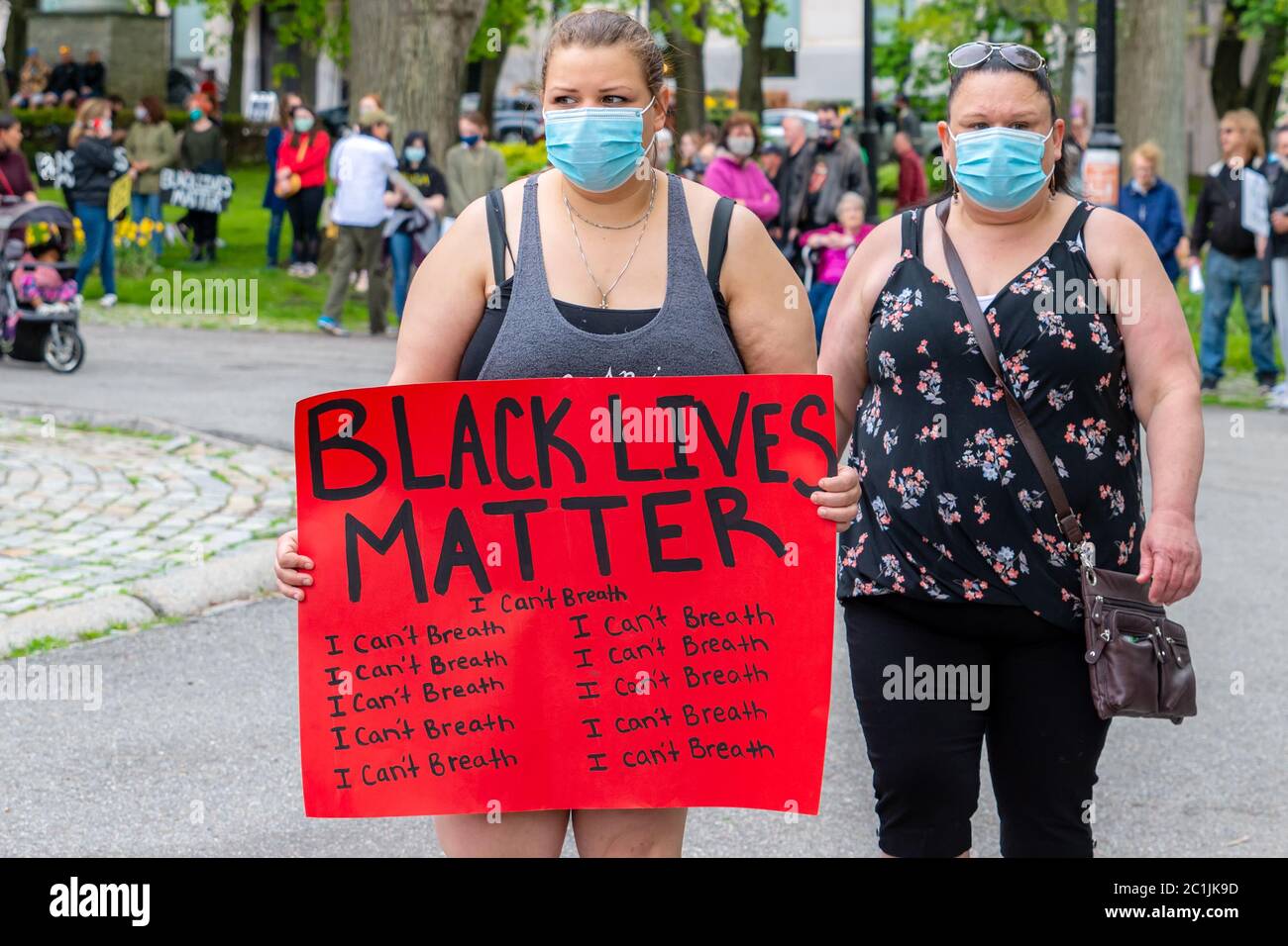 Saint John, NB, Kanada - 14. Juni 2020: Black Lives Matter Rallye. Zwei Frauen tragen Masken, eine trägt ein Protestschild. Stockfoto