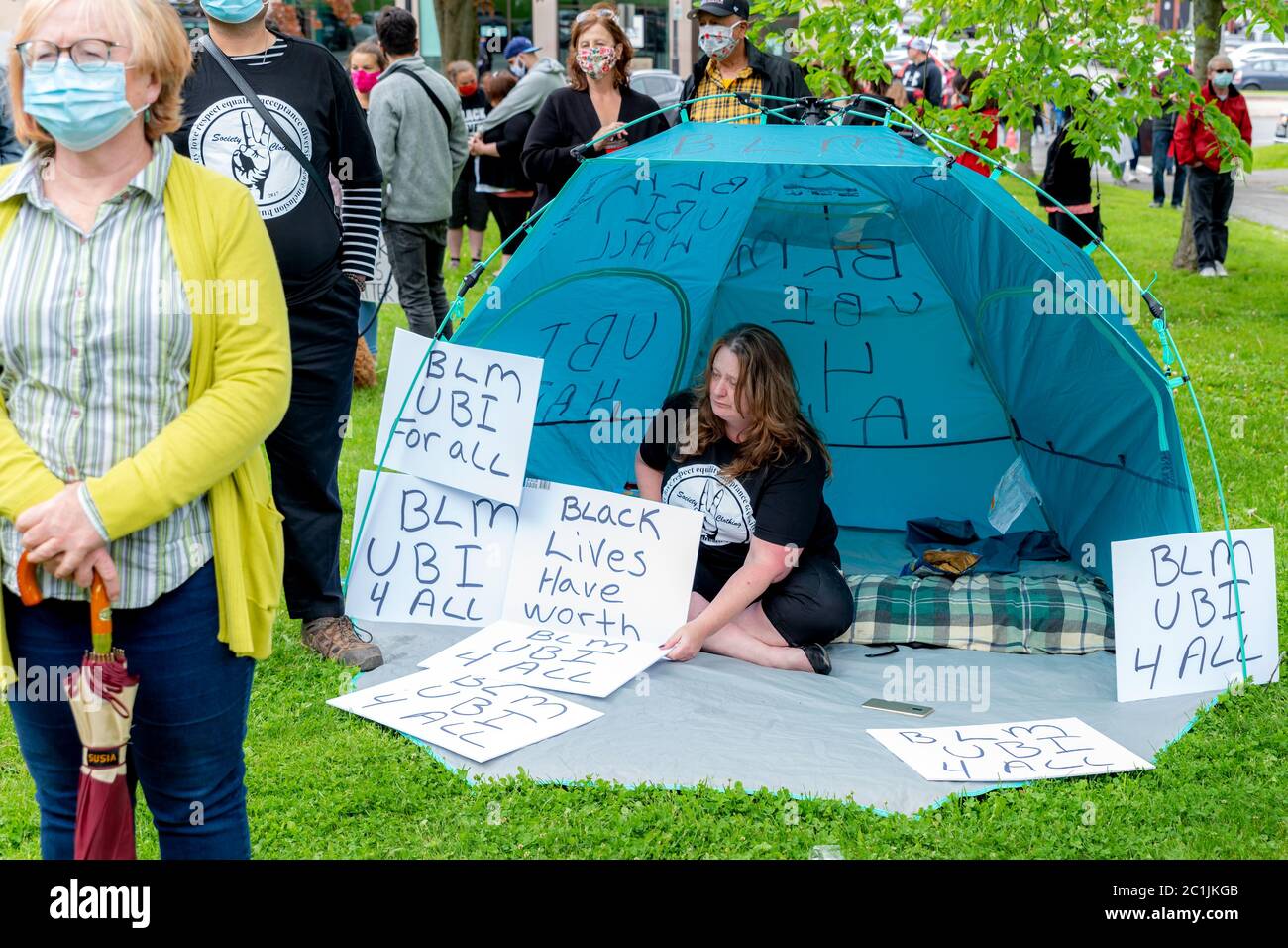 Saint John, NB, Kanada - 14. Juni 2020: Black Lives Matter Rallye. Eine Frau sitzt in einem blauen Zelt, umgeben von Schildern. Stockfoto