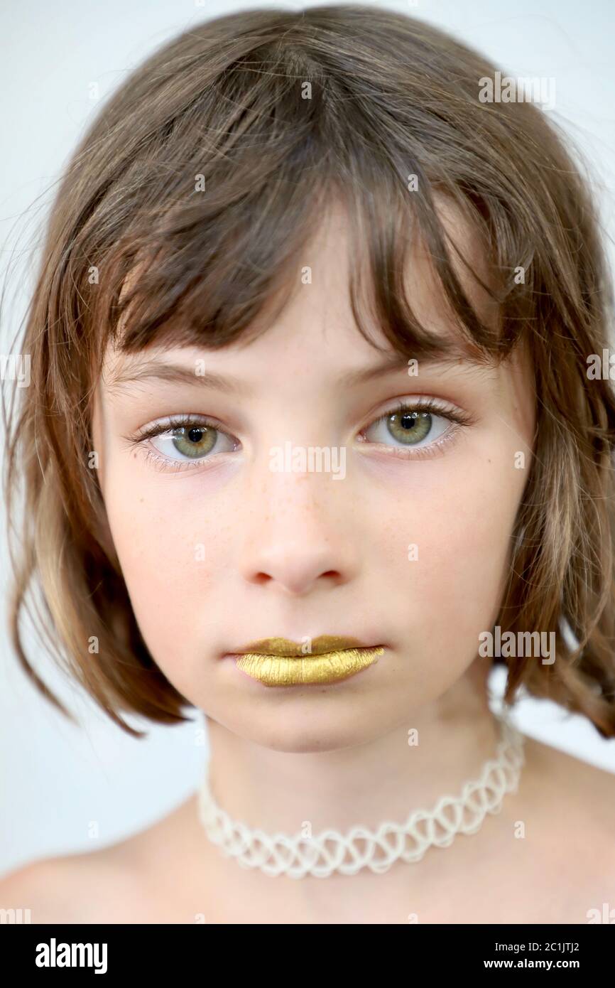 Ist Stille golden? Porträt eines Kindes mit versiegelten goldenen Lippen und intensivem Anstarren. Stockfoto