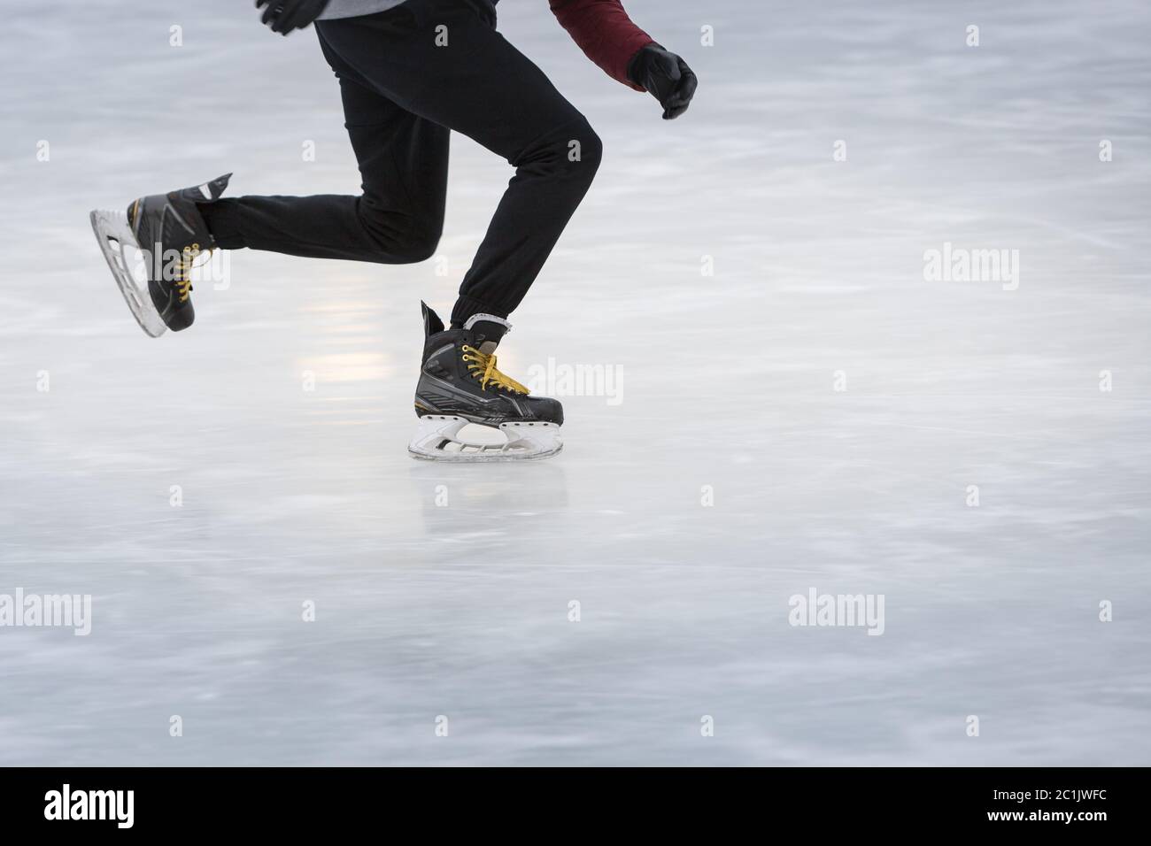 Nahaufnahme der Beine auf Schlittschuhen im Winter auf einer offenen Eisbahn in Bewegung, Seitenansicht, Kopierraum. Winter, Outdoor-Aktivitäten Konzept Stockfoto