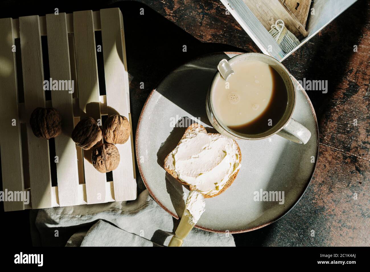 Schuss von oben von leckeren Stück Brot mit Butter und Marmelade auf dem Tisch mit Walnüssen und frischem Kaffee platziert Stockfoto