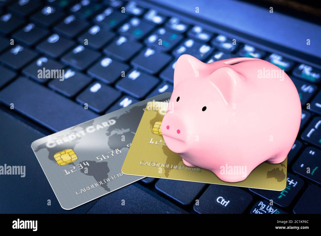 Pink Sparschwein auf der Oberseite der fiktiven Kreditkarten auf Computer-Tastatur zu illustrieren Kreditklemme, finanzielle Kreditaufnahme, Online-Shopping und Ersparnisse c Stockfoto
