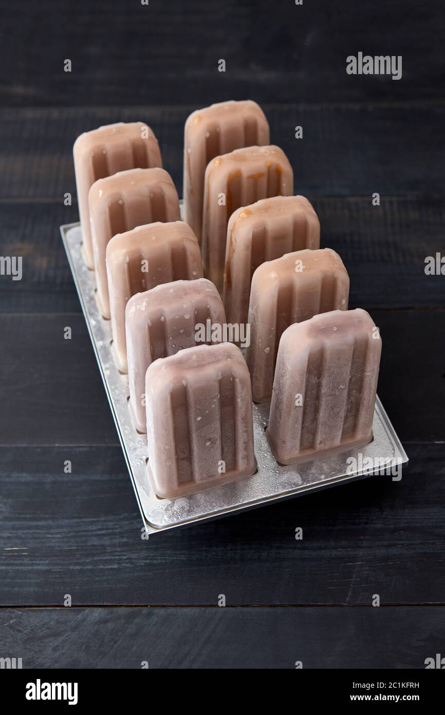 Eis am Stiel. Schokolade Hausgemachtes Sorbet in Kunststoff Form auf einem schwarzen Holz- hintergrund Kopie Platz für Text. Ansicht von oben Stockfoto