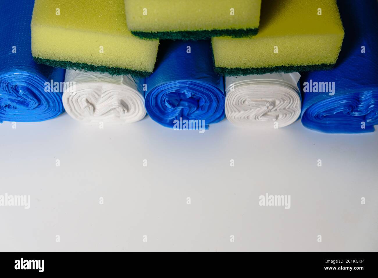 Reinigungseinrichtungen während der Isolierung von Coronaviren. Gelbe Spülschwämme und bunte Plastikmüllbeutel. Tägliche Hausfrau Küchenausstattung Stockfoto