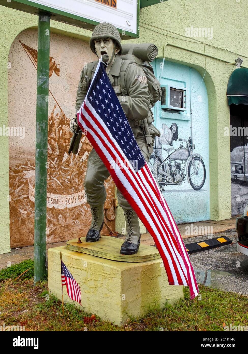 Eine Statue eines schreienden US-Soldaten mit US-Flagge wird mit einem Wandgemälde der Schlacht von Iwo Jima und einem Pin-up-Mädchen mit einem Motorrad in t gegenübergestellt Stockfoto
