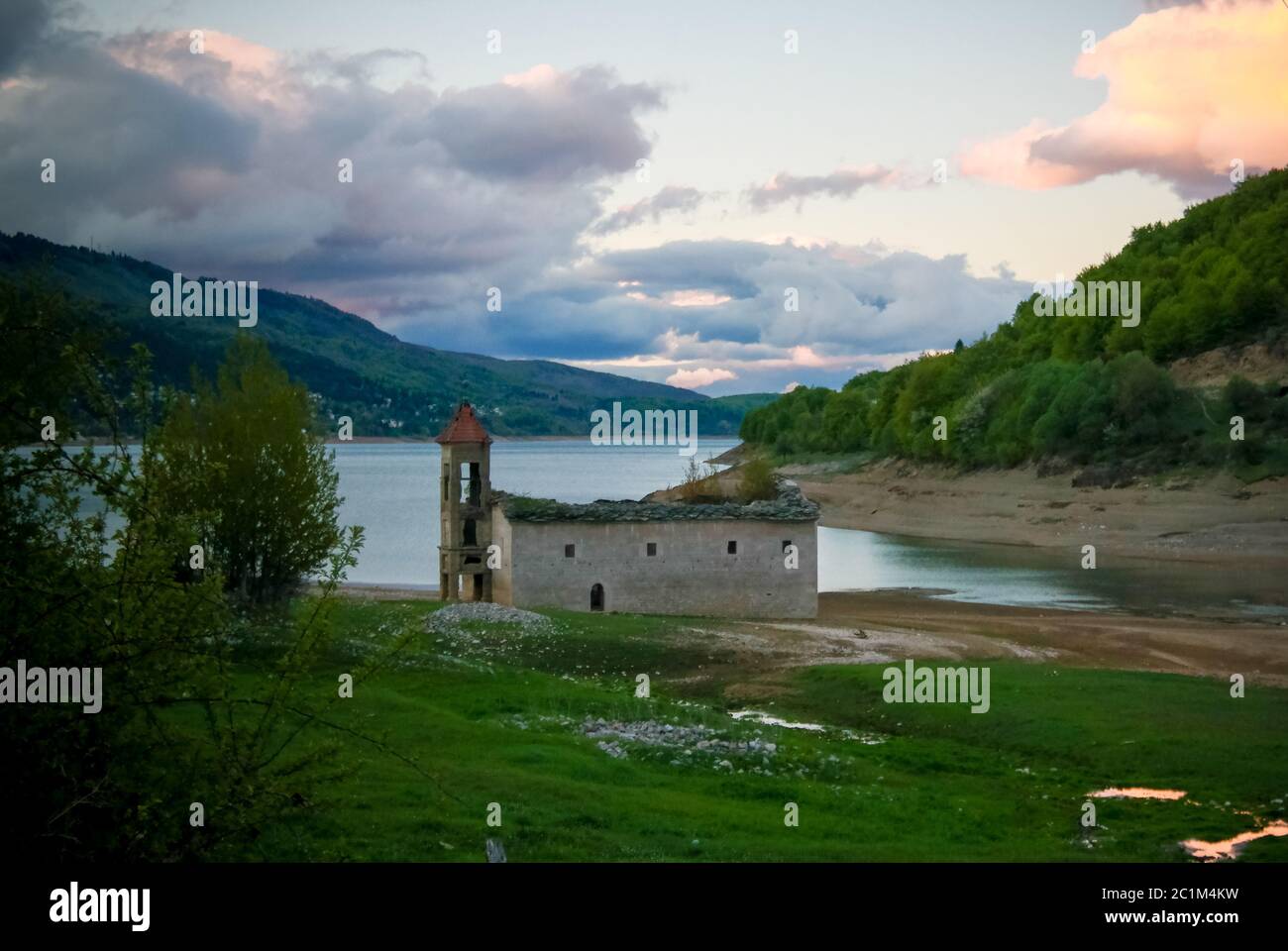 Sonnenuntergang Landschaft des Mavrovo Nationalparks mit Berg, See und alte ruinierte Kirche, Fyr Mazedonien Stockfoto