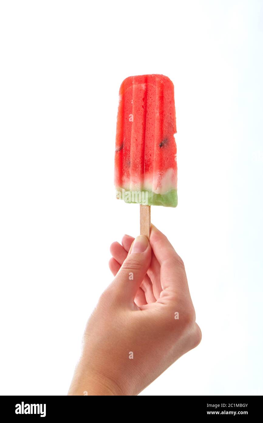 Hand eines Mädchens mit einem Stück saftige Wassermelone, Obst Eis lolly auf weißem Hintergrund mit einer Kopie. Dessert Stockfoto Hand eines Mädchens mit einem Stück saftige Wassermelone, Obst Eis lolly auf weißem Hintergrund mit einer Kopie. Dessert Stockfoto