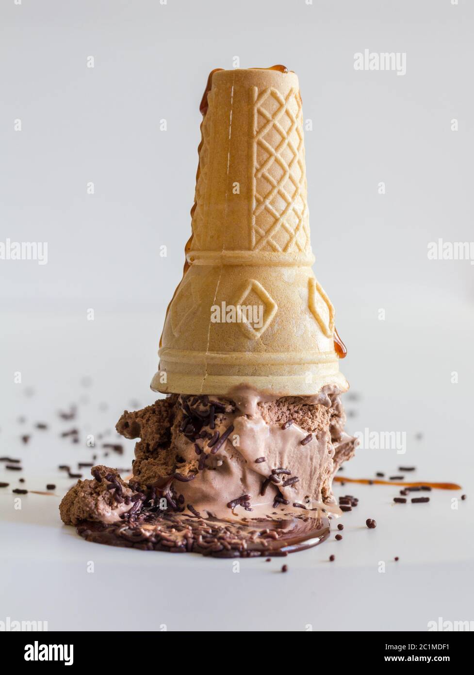 Eiskegel mit Schokoladeneis und Schokoladenstreuseln mit Karamellsirup nach oben Stockfoto
