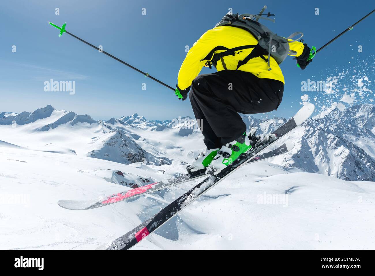 Ein Skifahrer in voller Sportausrüstung springt in den Abgrund von der Spitze des Gletschers vor dem Hintergrund des blauen Himmels und der Stockfoto