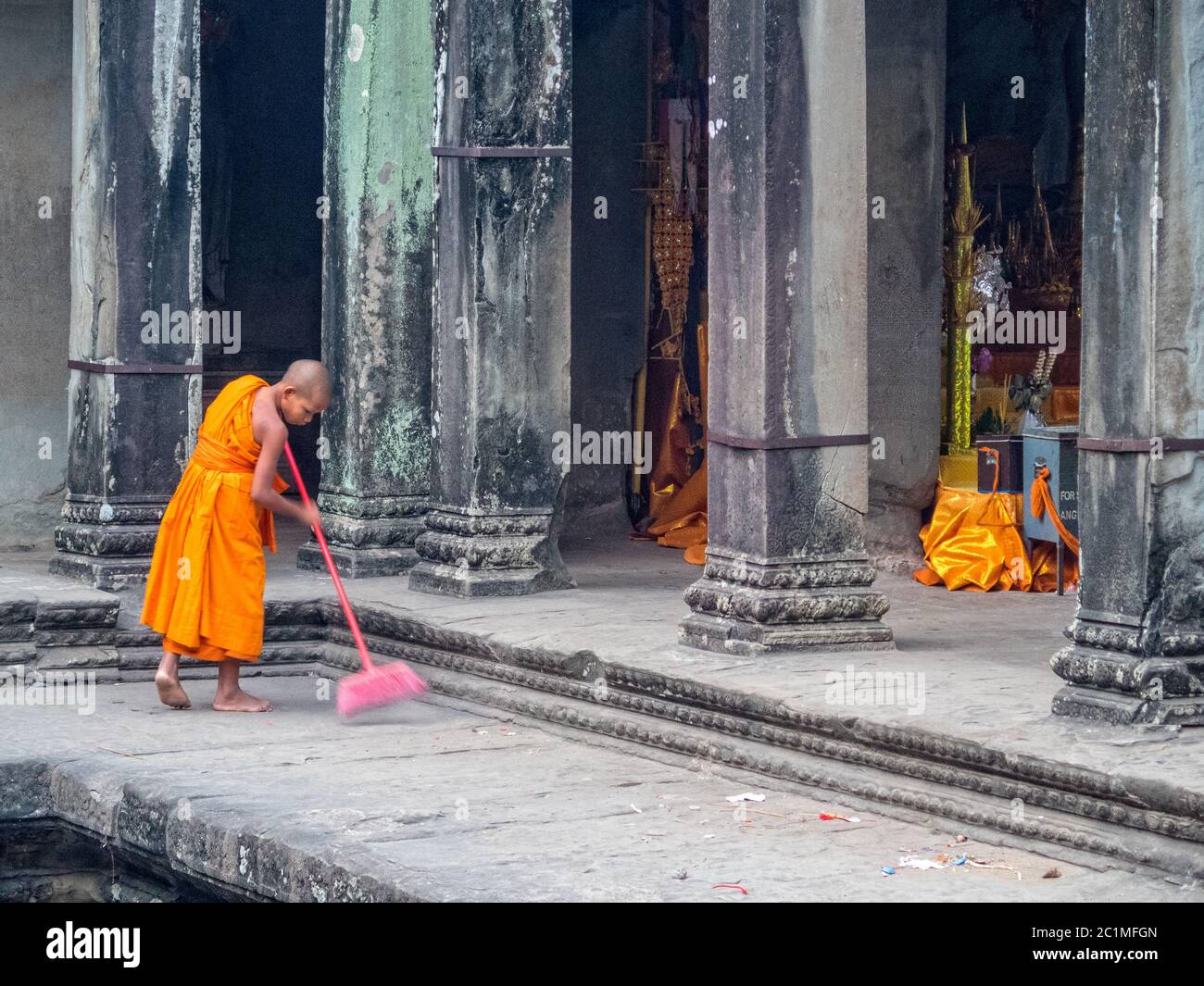 Junger Mönch in orangefarbener Robe, der früh morgens im Angkor Wat - Siem Reap, Kambodscha fegt Stockfoto