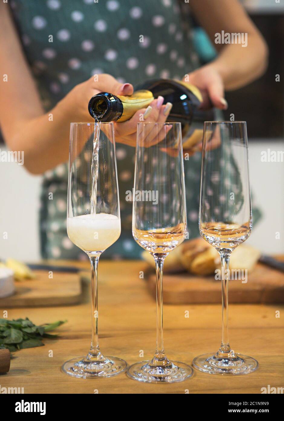 Frau gießt Champagner in Glas mit Blasen Stockfoto