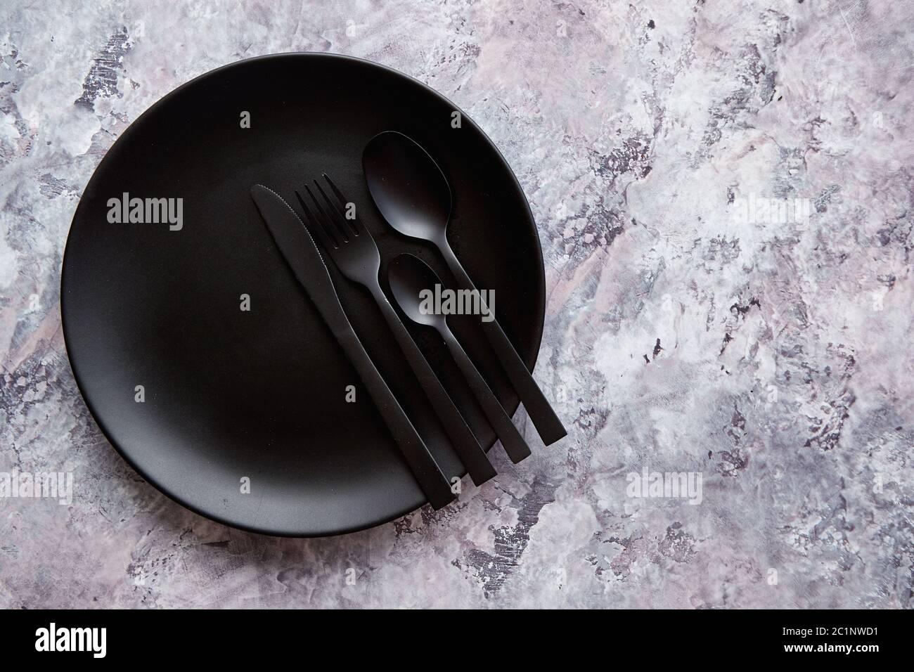 Blick von oben auf die schwarze Leere Platte auf Marmor Stein Hintergrund Stockfoto