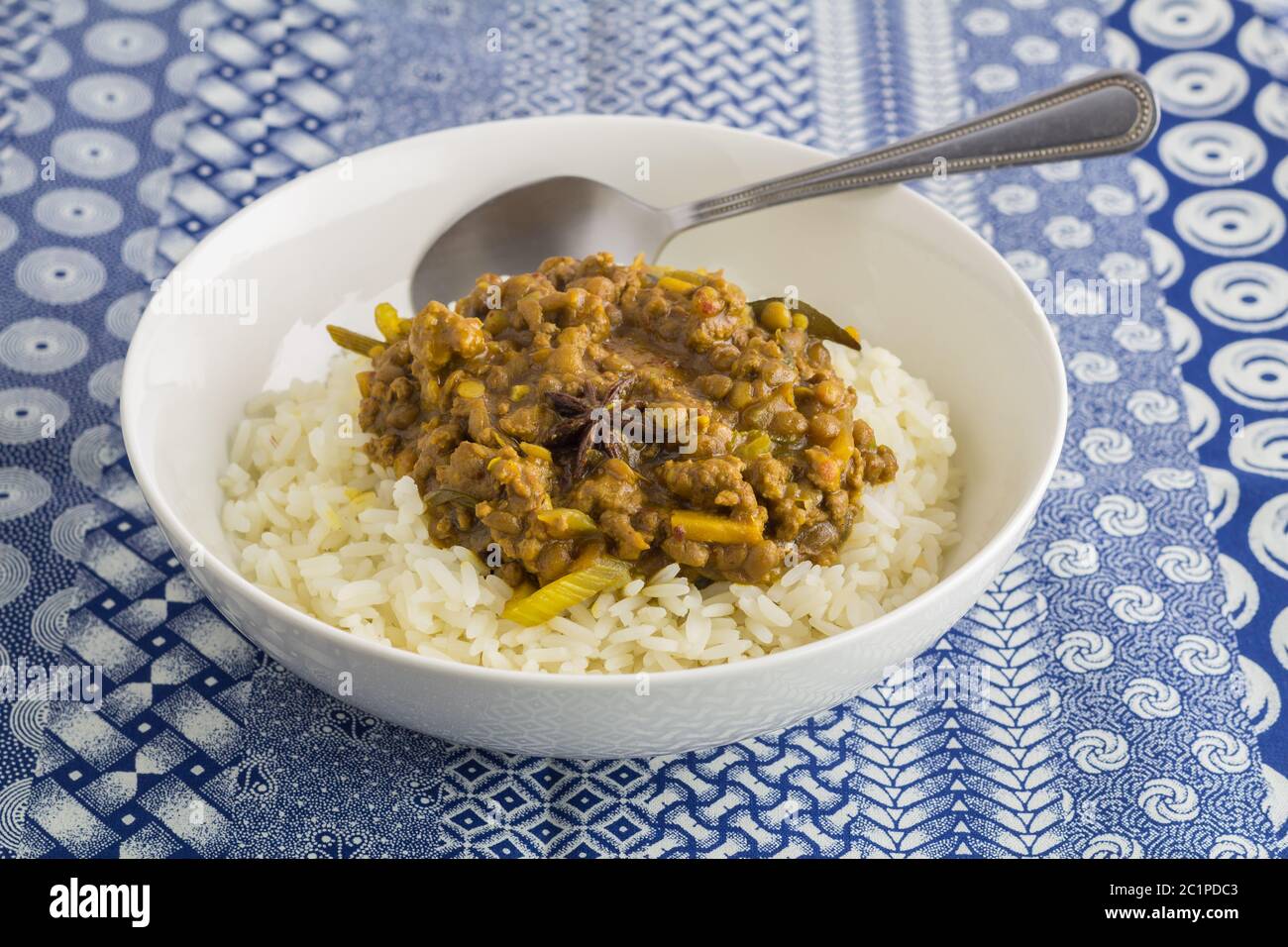 Linsengemüse Curry und Reis Nahaufnahme auf Indigo Ethnic gedruckt blau und weiß Tischdecke Backgrou Stockfoto