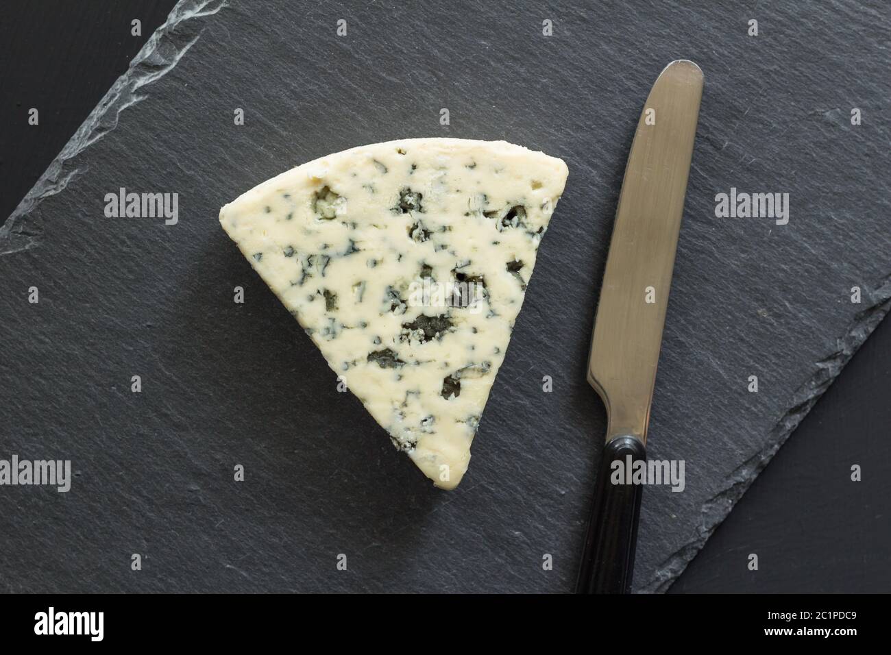 Blue Cheese Triangle mit Messer isoliert auf schwarzem Schiefer Käse Board - Roquefort Typ Käse top vie Stockfoto