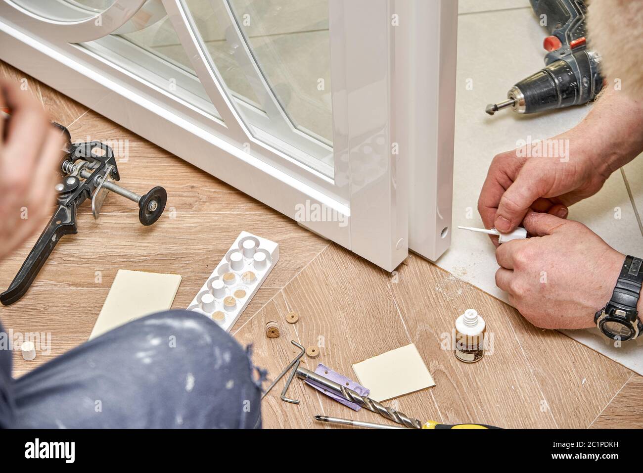 Reparatur der Schiebetüren aus Glas. Arbeiter installieren Endkappe. Weiße Glasschiebetüren mit Überzügen. Nahaufnahme Stockfoto