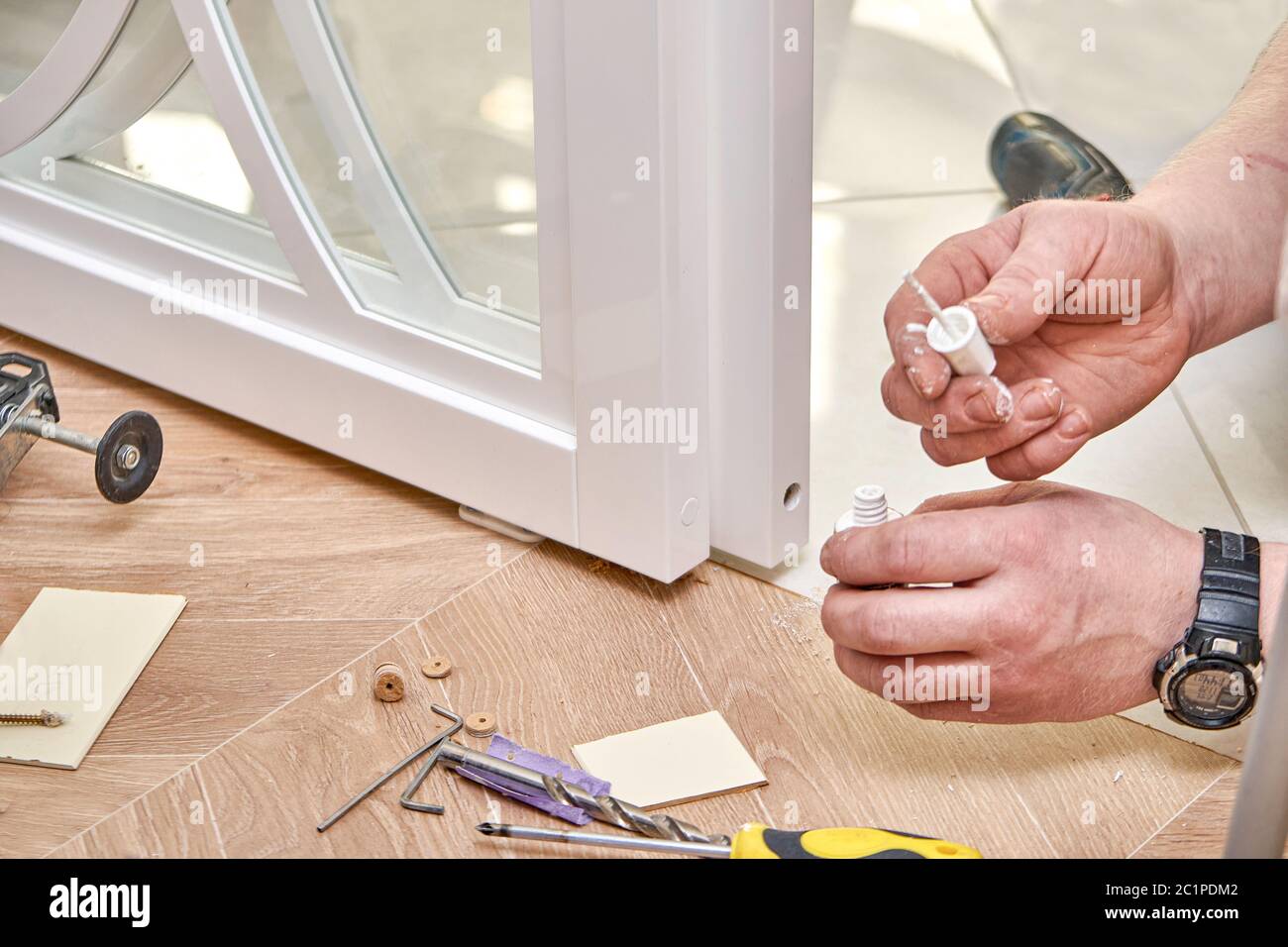 Reparatur der Schiebetüren aus Glas. Arbeiter installieren Endkappe. Weiße Glasschiebetüren mit Überzügen. Nahaufnahme Stockfoto