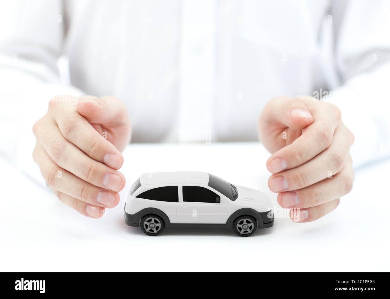 Auto Versicherung Konzept mit weißen Auto Spielzeug von Händen bedeckt Stockfoto