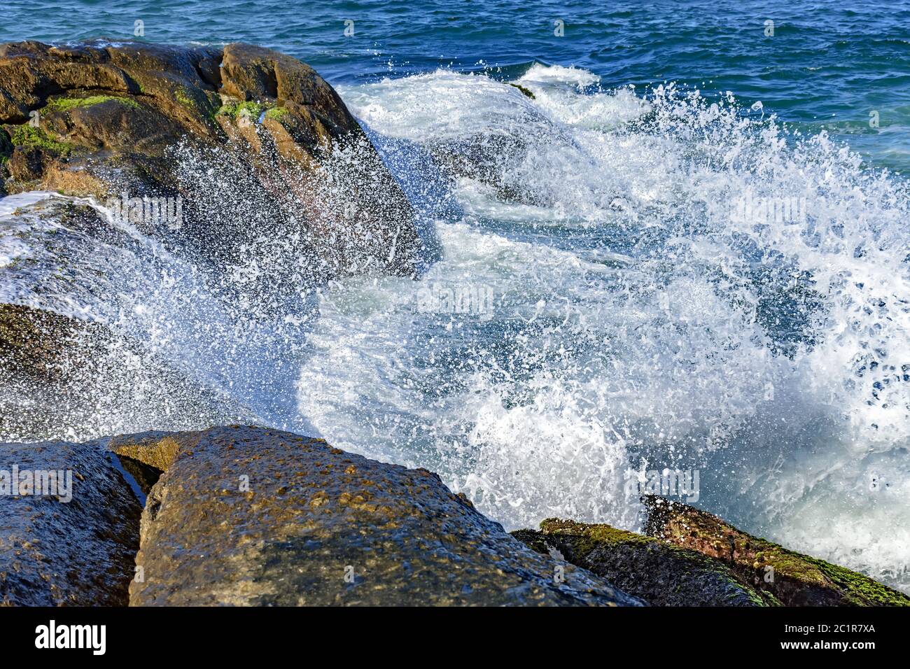 Wellen krachen über Felsen mit Wassertropfen Stockfoto