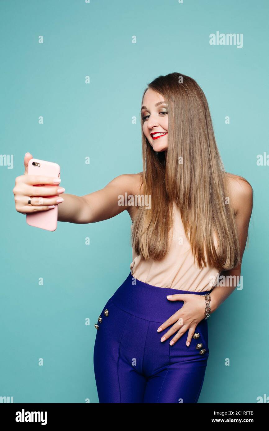 Pretty Woman nimmt selfie per Handy über grünen Hintergrund. Stockfoto