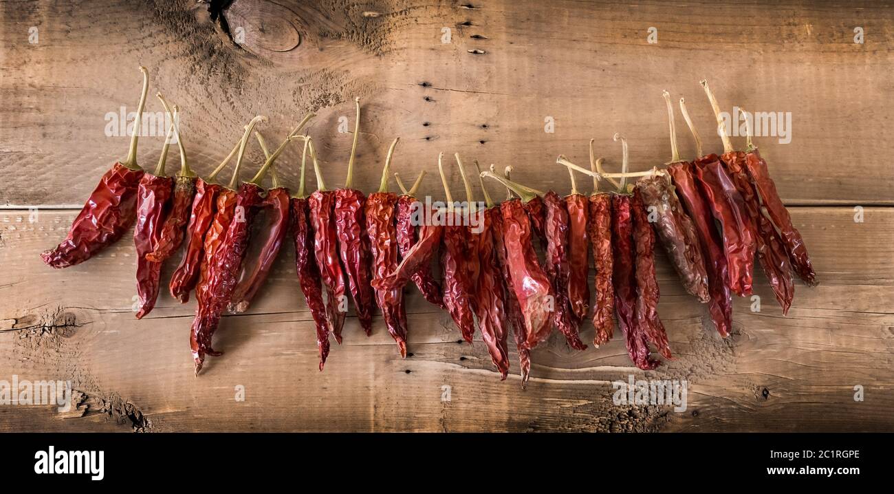 Schnur getrockneter roter Chilischoten auf Holzhintergrund Stockfoto